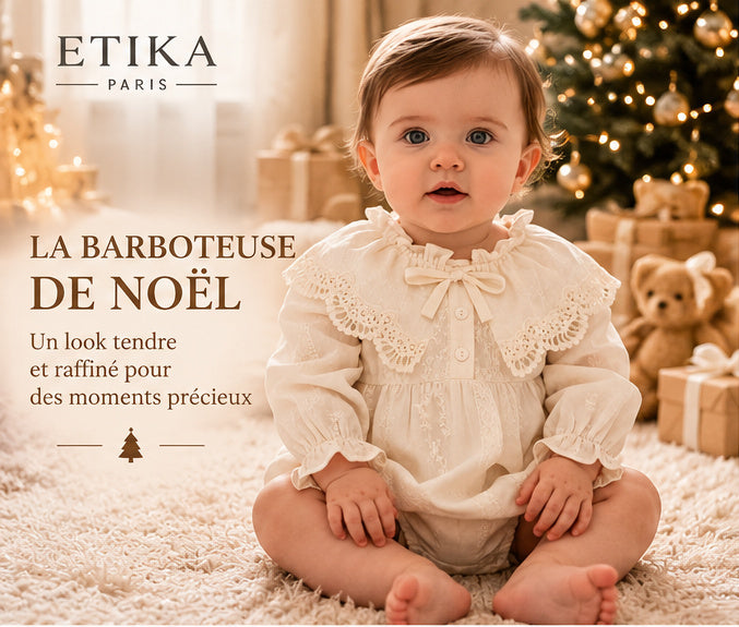Bébé en barboteuse ivoire devant le sapin pour son premier Noël