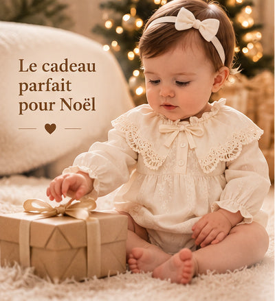 Le cadeau parfait pour Noël : bébé en barboteuse ivoire ouvrant un paquet
